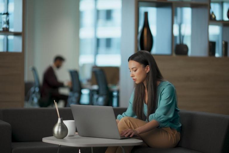 Persona utilizando un asistente de inteligencia artificial desde un ordenador portátil mientras analiza información en un entorno de trabajo digital. La imagen representa la creciente interacción entre las personas y la IA para comunicarse, aprender y resolver problemas.