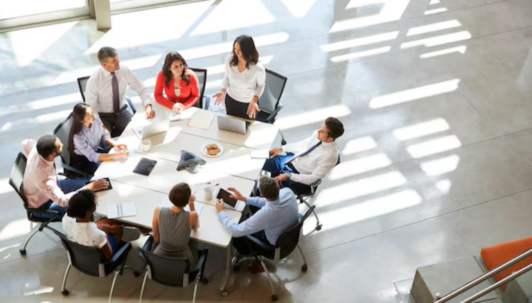 Equipo de profesionales colaborando en un entorno corporativo mientras analizan información y herramientas digitales. La imagen representa la necesidad de alinear liderazgo, formación y adopción tecnológica para impulsar el uso de la inteligencia artificial en toda la organización.